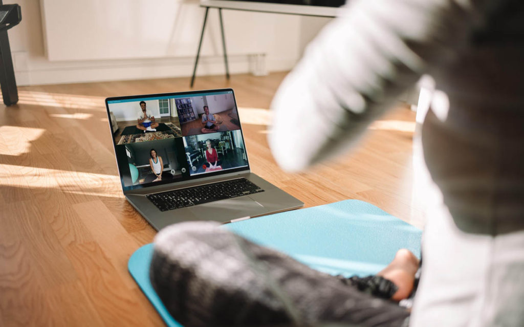 Profesora freelance dando clase online bonificadas de yoga a través de una videoconferencia.